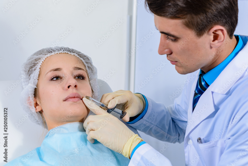 Facial rejuvenation procedure - man doctor injects injections of hyaluronic acid into nasolabial folds to young woman client Facial rejuvenation procedure - man doctor injects injections of hyaluronic acid into nasolabial folds to young woman client