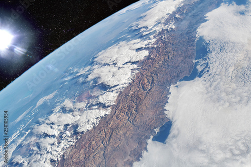 Fototapeta Naklejka Na Ścianę i Meble -  Cloud-covered Pacific coast of the South American nation of Chile contrasts with the Andes Mountain range and the cloud formations extending over Argentina. Elements of this image furnished by NASA.
