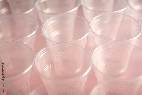Many white disposable plastic cups on pink background. Flat lay.