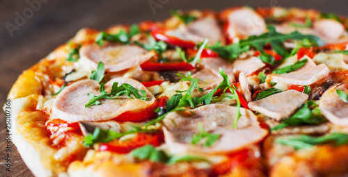 Pizza with Mozzarella cheese, mushrooms, ham, tomato sauce, pepper, Spices and Fresh arugula. Italian pizza on wooden table background