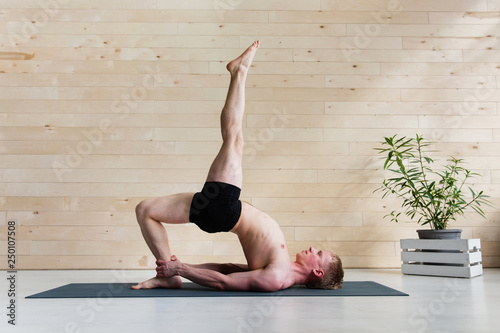 Sporty man practicing yoga on yoga class, bridgepose photo