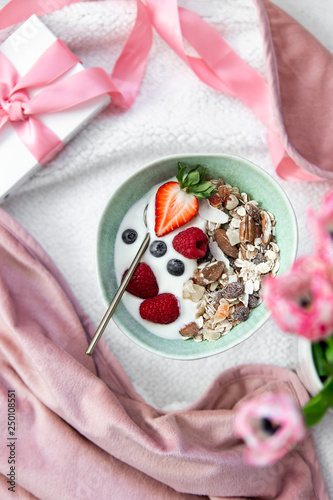 Start the day the healthy way. Granola, yogurt and berries in a beautiful green rustic plate with copy space