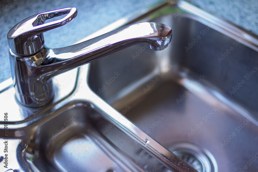 Licht fällt auf den Wasserhahn eines Chrom Spülbeckens in einer modernen Küche Licht fällt auf den Wasserhahn eines Chrom Spülbeckens in einer modernen Küche