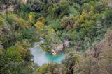 View from above of the river with urquiose waters flowing amobg colorful green and yellow trees in the mountains of Gregorian villa in Tivoli, Italy