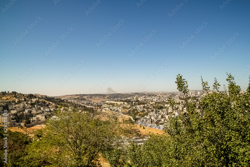 Distant view of the cityscape of Old City of Jerusalem with smoke over the mountains and copy space above