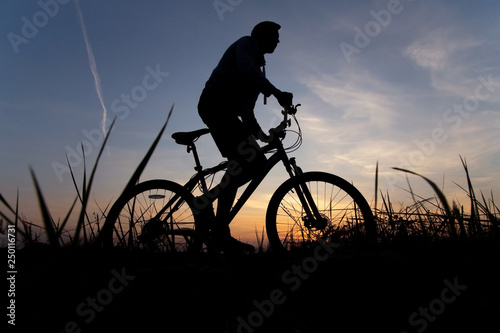 Man, silhouette of a cyclist riding on mountain bike against the sunset sky. Sport, fitness outdoor