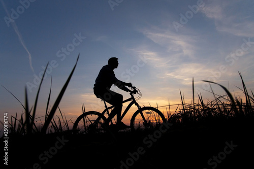 Silhouette of a cyclist against the sunset sky, copy space