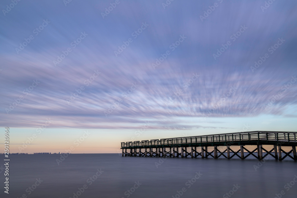 Dramatic beach scenery featuring stormy sky over the fishing pier at New Jersey shore. Shot using slow shutter speed