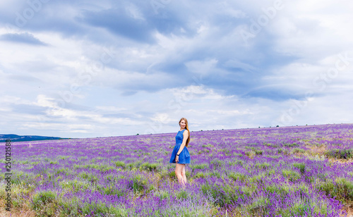 Fototapeta Naklejka Na Ścianę i Meble -  Girl in blue dress on lavender field in cloudy weather