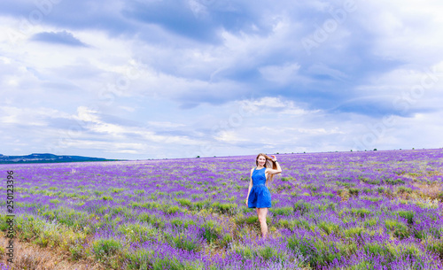Girl in blue dress on lavender field in cloudy weather