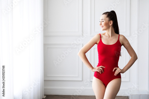 Beautiful brunette woman posing in red lingerie, bodysuit.