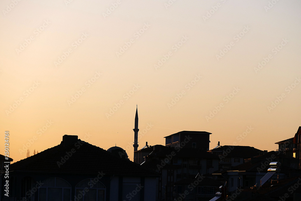 a Turkish city and a minaret of a mosque at sunset