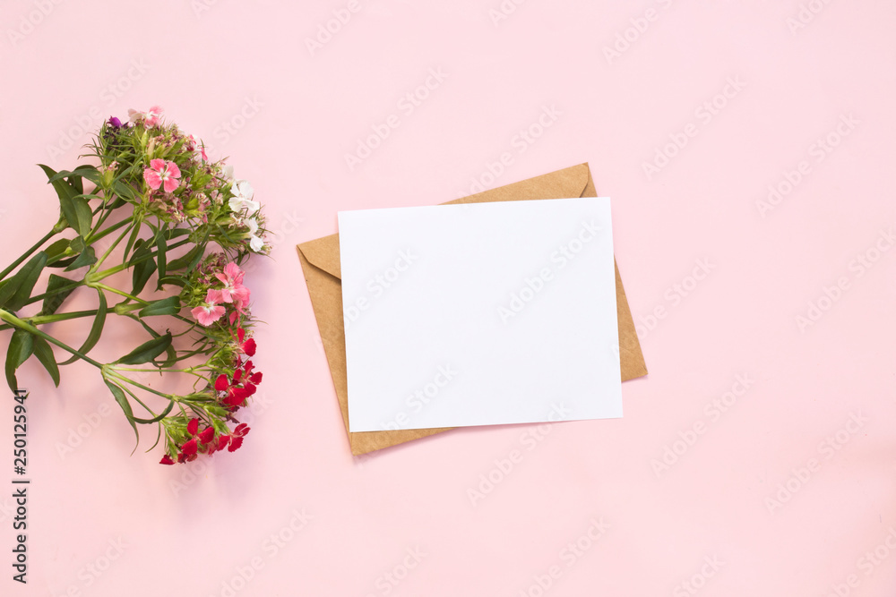 Top view of envelope and blank greeting card with flowers on pink background. Top view of envelope and blank greeting card with flowers on pink background.