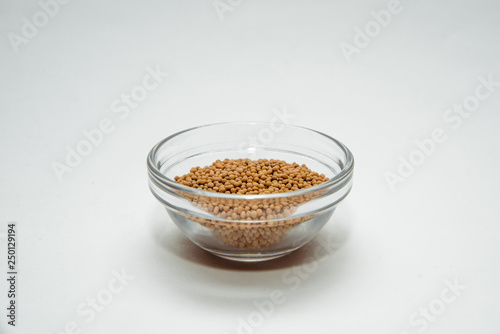 Mustard in a bowl isolated on white. Mustard located on a white table. The concept of using seasonings for dishes. Eating spiced dishes.