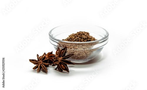 Grains of anise and anise stars in a bowl on a white background. Anise put on the table. The concept of using seasonings for dishes. Eating spiced dishes.