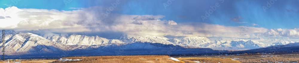 Winter Panoramic view of Snow capped Wasatch Front Rocky Mountains, Great Salt Lake Valley and Cloudscape from the Bacchus Highway. Utah, USA.