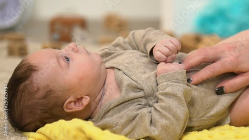 Lady tickling and massaging kids tummy, playing with charming baby, happiness photo