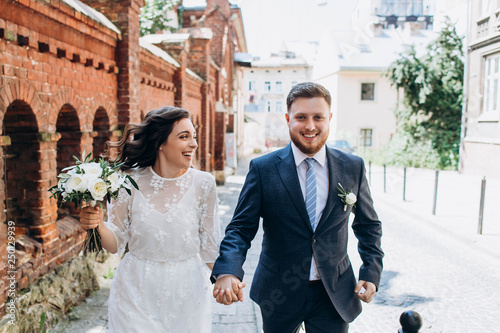 A beautiful wedding couple in the retro style sincerely have fun. Happy bride and groom have fun running together