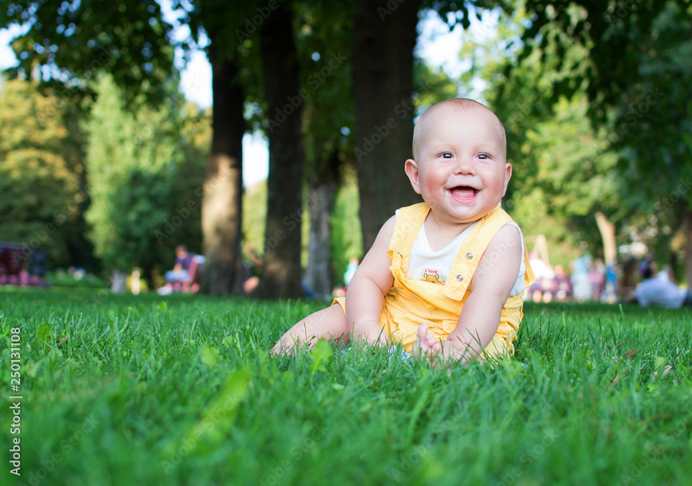 A smiling child is sitting in the park on the green grass. Concept for diapers. Happy child A smiling child is sitting in the park on the green grass. Concept for diapers. Happy child