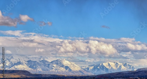 Winter Panoramic view of Snow capped Wasatch Front Rocky Mountains, Great Salt Lake Valley and Cloudscape from the Bacchus Highway. Utah, USA.