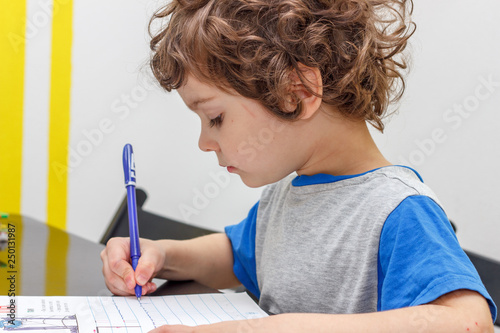 the lovely curly-headed boy writes copy-books, letters