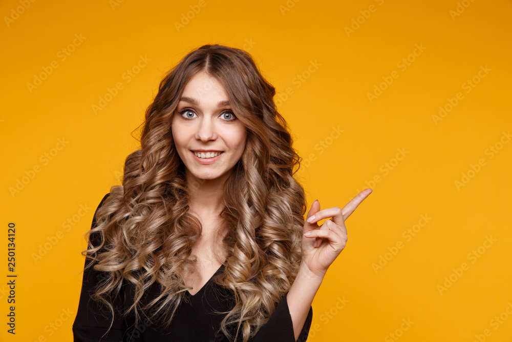 Obraz premium Closeup portrait of pretty yong woman with bright makeup in a studio isolated over the yellow background