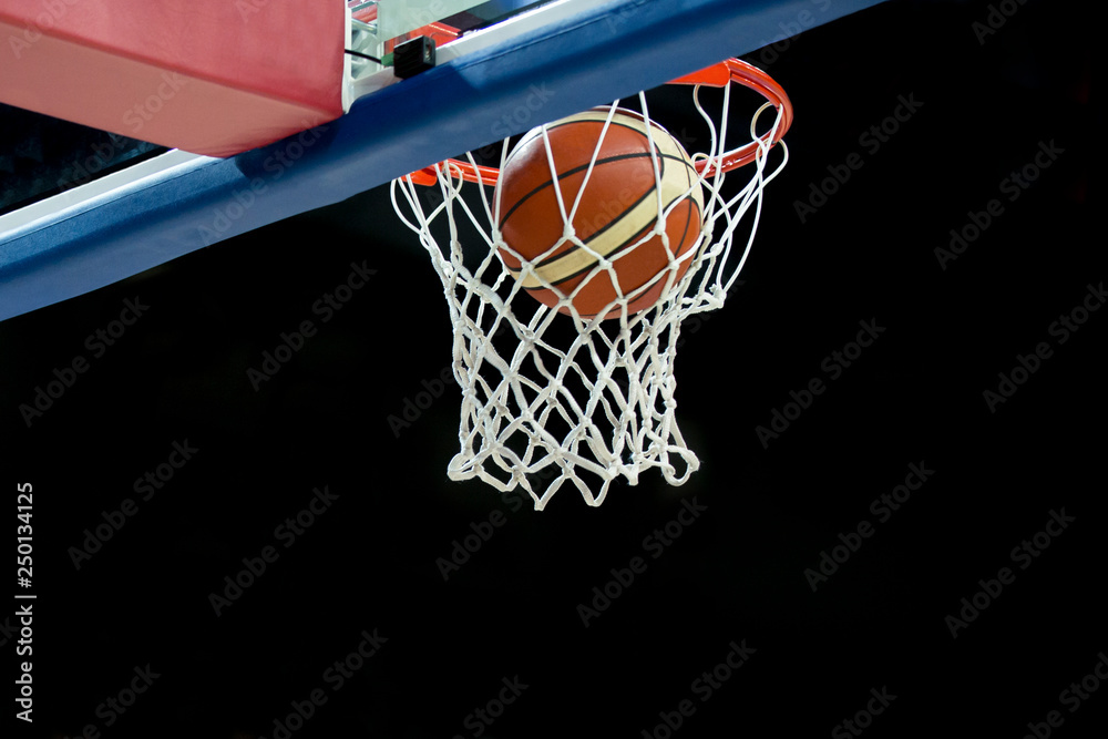 The orange basketball ball flies through the basket