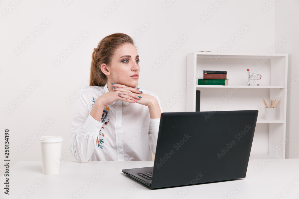 Young businesswoman in a white blouse sitting in an office. Office worker sitting infront of black computer. Coffee in office. Young businesswoman in a white blouse sitting in an office. Office worker sitting infront of black computer. Coffee in office.