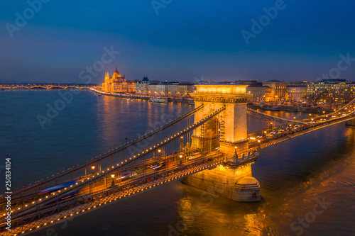 Budapest, Hungary - Aerial view of the famous illuminated Szechenyi Chain Bridge at blue hour with Parliament building at the background and clear blue sky