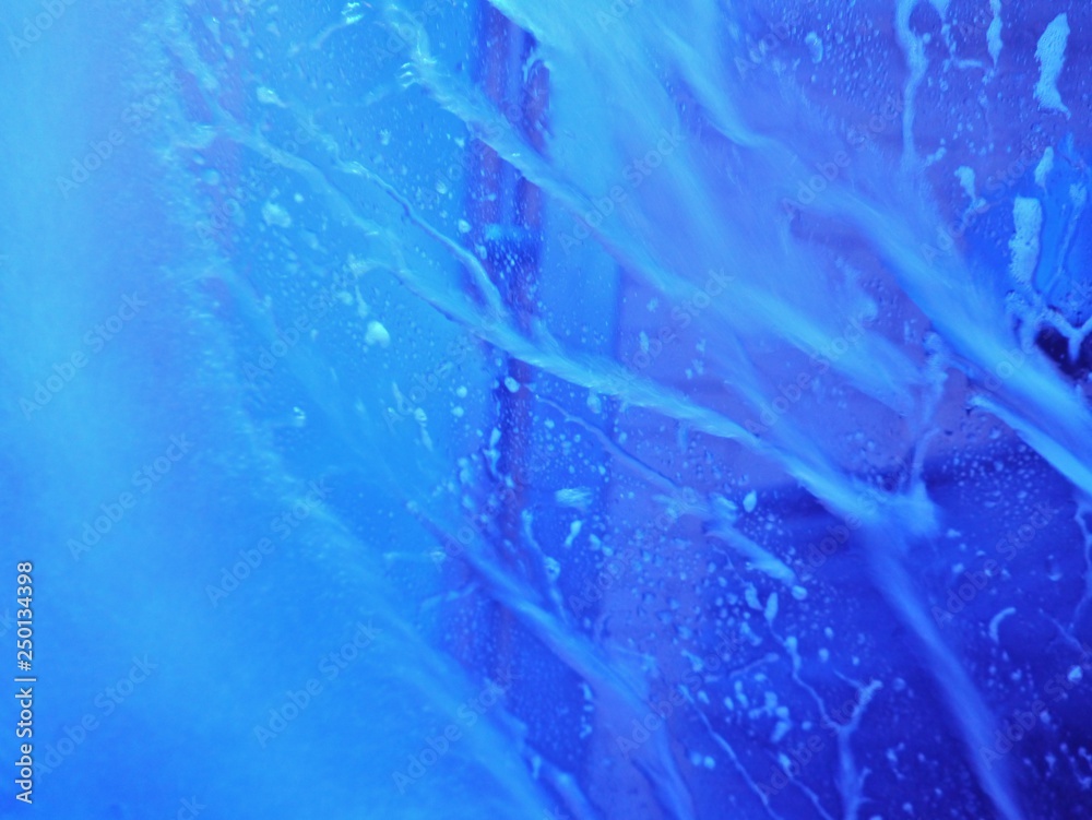 Wasser fließt an blau beleuchteter Windschutzscheibe