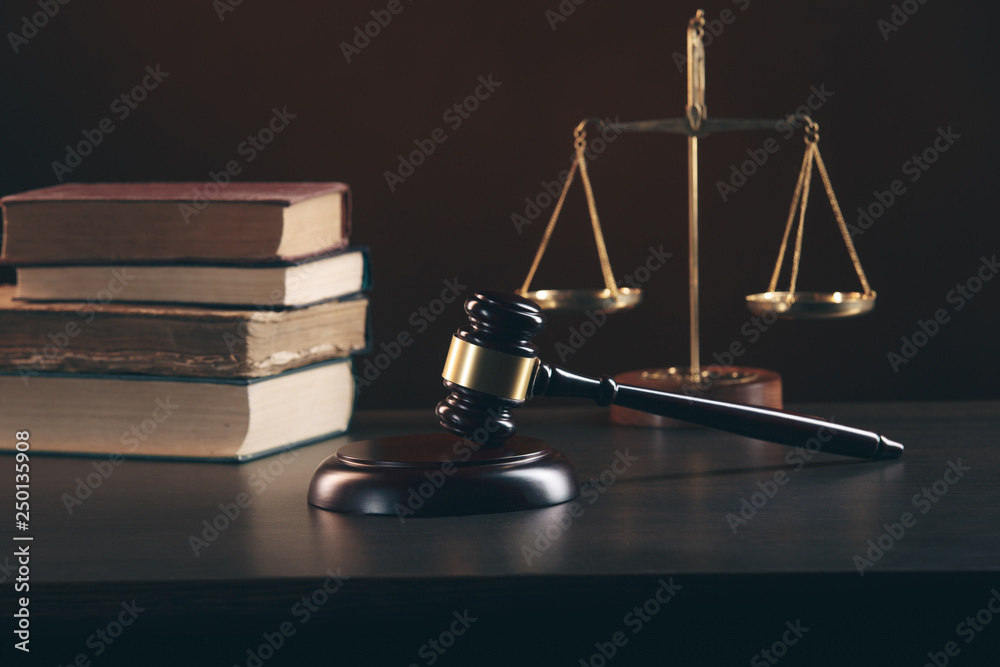 Judge gavel and book with Justice lawyers having team meeting at law firm in background Judge gavel and book with Justice lawyers having team meeting at law firm in background