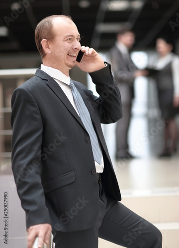 smiling businessman talking on mobile phone in office