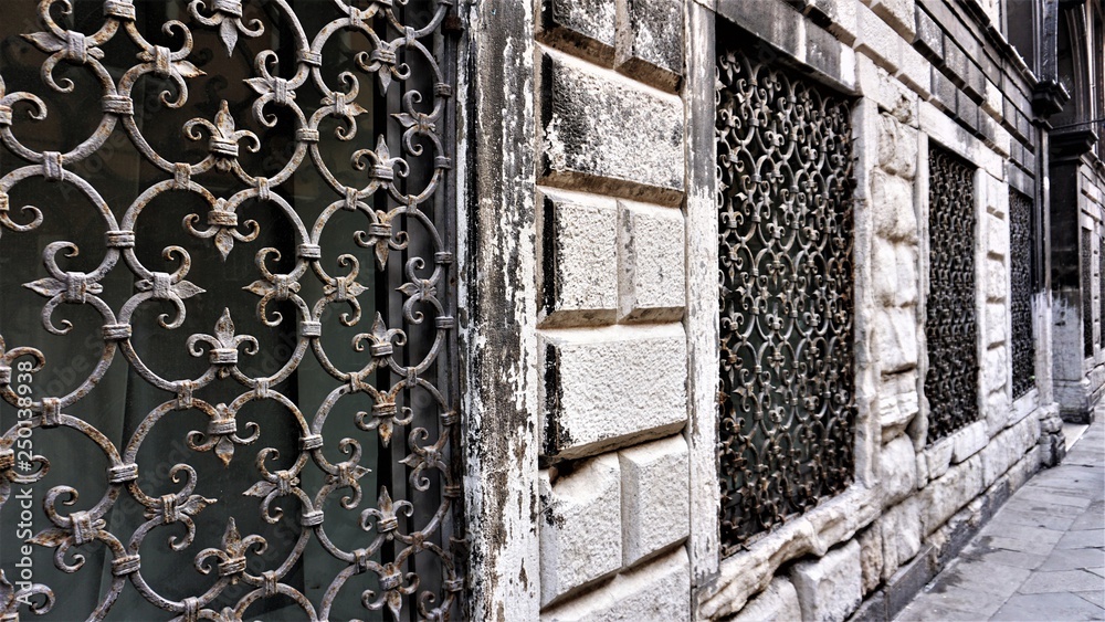Window with a decorative metal grid of old Venetian times on the wall of an old building, architectural detail Window with a decorative metal grid of old Venetian times on the wall of an old building, architectural detail