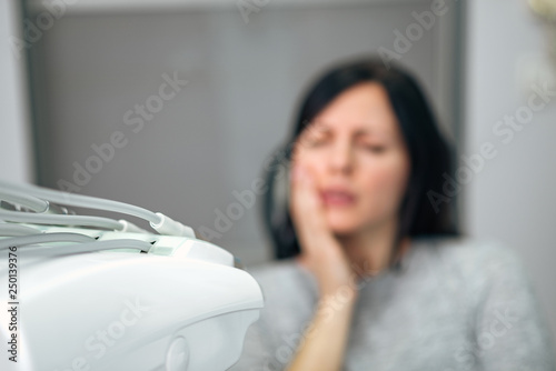 Medicine, dentistry and healthcare concept. Woman with tootache at dental clinic, focus on the foreground, on medical equipment. photo