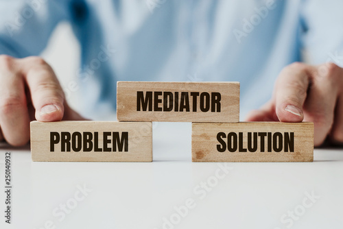 Hand holding a wooden jigsaw puzzle with conflict and Mediator word. There is a matching puzzle next to it. The concept of solving problems, all problems can be solved, connection.