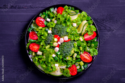 Fresh salad with various vegetables on dark background.