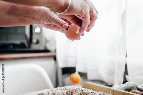 A woman smashes an egg, uses a yolk. Punching eggs for cake preparation. Concept of baking and preparing a cake for baking. Adding eggs as an ingredient to the dough. Baking gingerbreads.