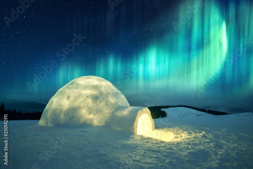 Aurora borealis. Northern lights in winter mountains. Wintry scene with glowing polar lights and snowy igloo photo