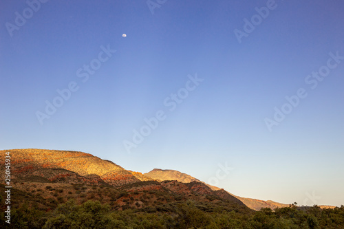 Redbank Gorge, West MacDonnell Ranges, Northern Territory; moon at sunset, dusk, over mountains photo