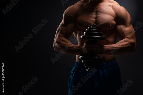 Athlete, bodybuilder, on a black background with a weight. Gym advertising, fitness, sports club. Banner. Concept of a healthy lifestyle