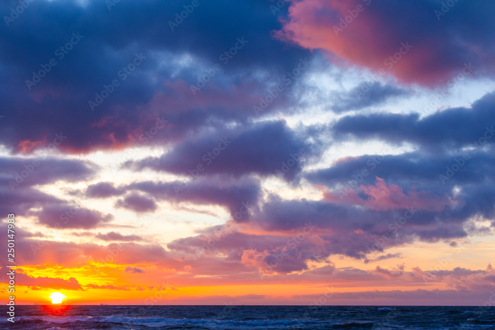 picturesque seascape with colorful clouds and bright sunshine during sunset