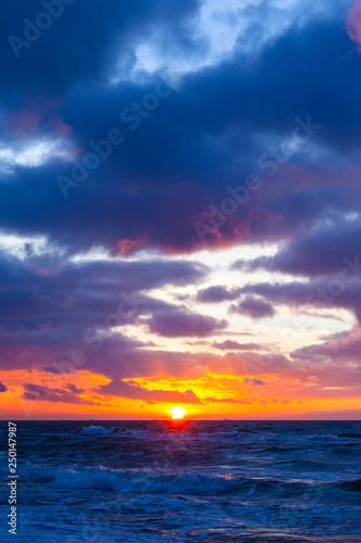 picturesque seascape with colorful clouds and bright sunshine during sunset