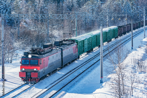 Freight train moves by the winter forest.