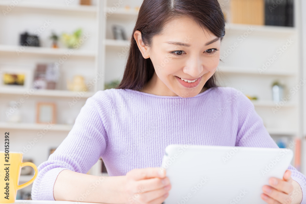 部屋でタブレットコンピューターを見る女性 部屋でタブレットコンピューターを見る女性