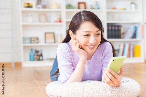 部屋でスマホを見る女性