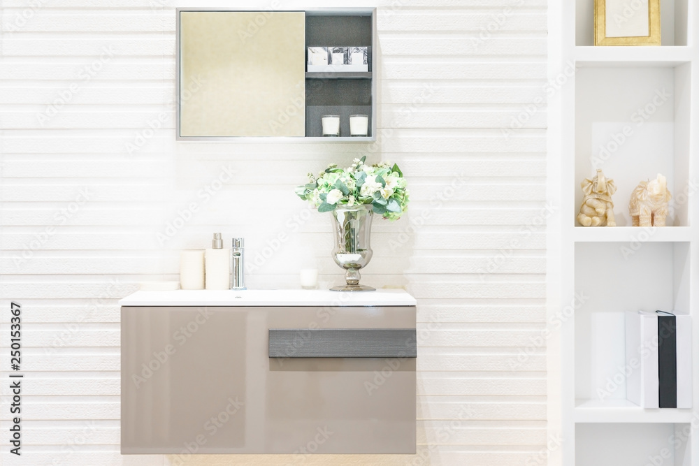 Fototapeta premium White bathroom sink standing on a wooden shelf. A square mirror hanging on a white wall, Close up