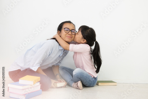 young mother and daughter sitting on floor white wall background. Adult education, Education Knowledge Concept