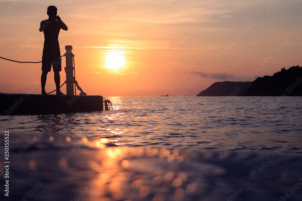 Asian man standing and jumping on floating pier at sunrise , Silhouette body of asian people early morning