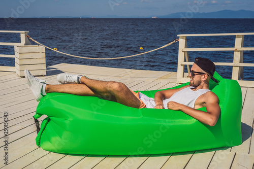 Young man enjoying leisure, lying on the air sofa Lamzac, near the sea photo