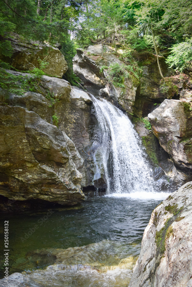 Scenic view of waterfall cascading into swimming hole Scenic view of waterfall cascading into swimming hole
